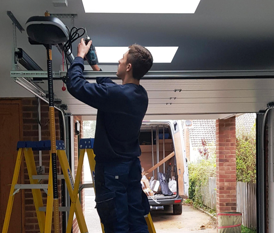 An engineer repairing a broken roller garage door.